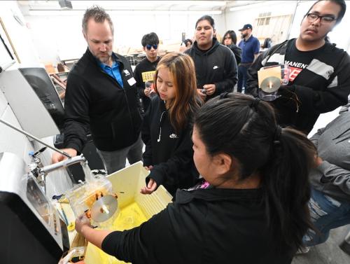 Students stand around a small model of a hydropower turbine.