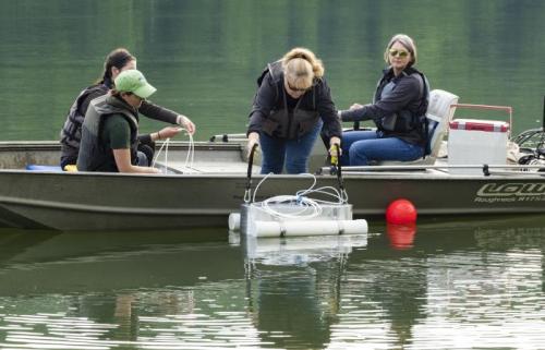 Researchers in a small boat deploy an instrument to collect emissions measurements.